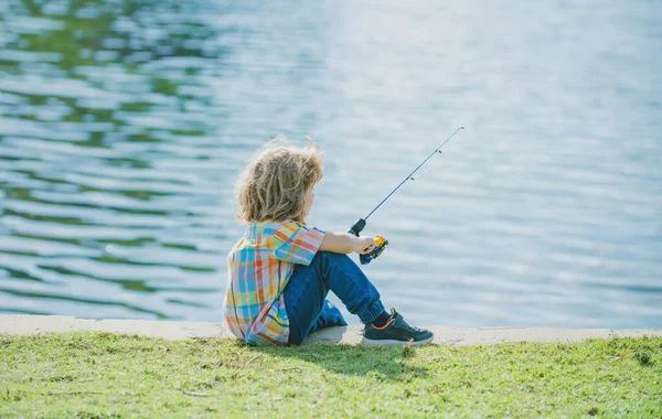 Vishobby. Kindervissen op het meer. Jongen met spinner bij River. Kind aan steiger met staaf. — Stockfoto