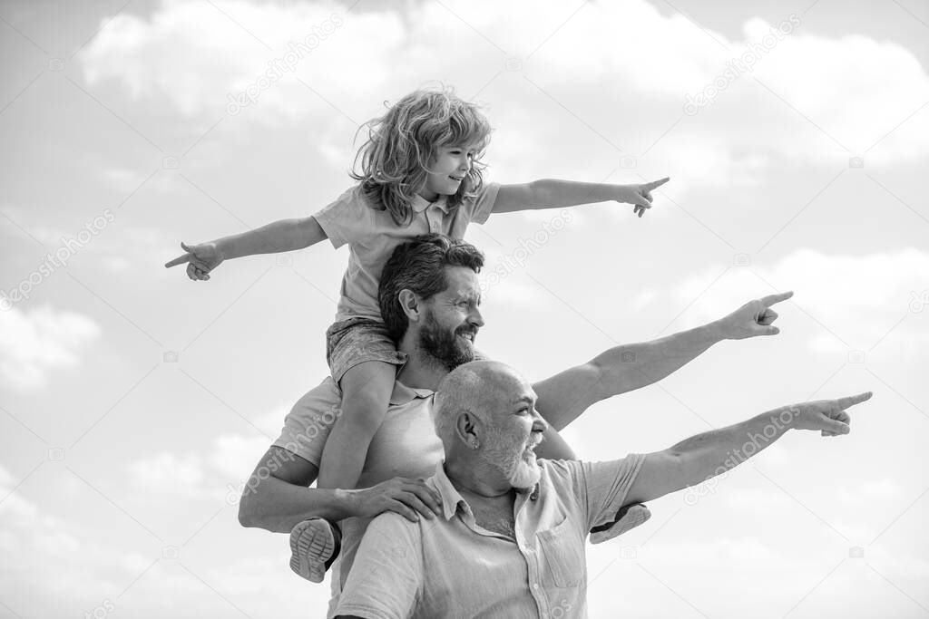 Father and son with grandfather was excited with pointing finger. Hand gestures point. Three generations of men having fun together outdoor.