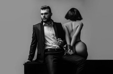 Cinsel ilişkiler. Seks oyunu. Dalga geç ve baştan. Seksi kız çıplak kalça. Tutkulu aşıklar. Seks hakimiyeti. Seks teslimiyeti. Maço bakımlı hipster ve çıplak seksi kadın elleri kırmızı kurdele bağlı