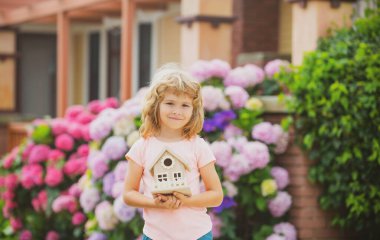Çocuk arka bahçedeki bir oyuncak evde oynuyor. Mutlu çocuk hayali yeni ev.