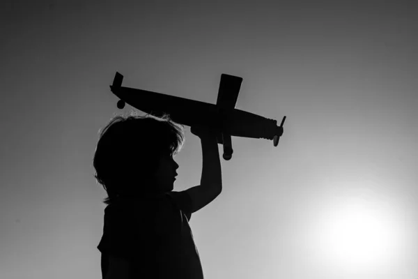 Kinderträume. Junge Pilot mit Spielzeugflugzeug, Silhouette. Kind spielt im Freien. Glückliche Kindheit. Tagträume. — Stockfoto