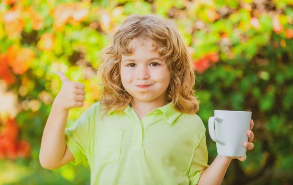 Garoto bonito desfrutar de xícara com chá de bebida ou leite na manhã de verão ensolarado fora. Crianças ao ar livre atividade de recreação saudável. — Fotografia de Stock
