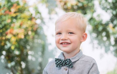 Küçük çocuk temiz havada eğleniyor. Takım elbiseli ve papyonlu çocuk. Mutlu anlar. Küçük çocuk hayatın ve doğanın tadını çıkarıyor. Komik çocuk..