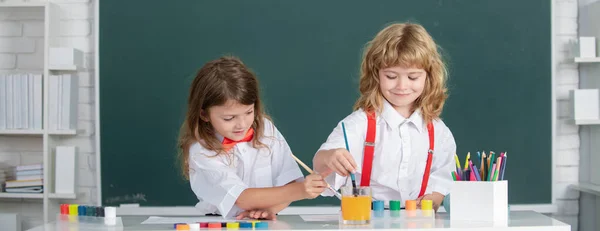 Barn flicka och pojke ritning med färgpennor. Söta skolbarn måla i klassen i skolan. — Stockfoto