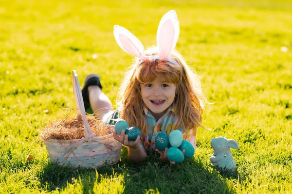 Vrolijk Pasen. Kids jongen in konijnenoren jagen op paaseieren buiten. Kind met Pasen in het park. Paaseieren jacht. — Stockfoto