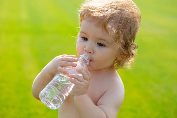 Dziecko pije wodę z butelki podczas spaceru po trawie, zdrowie dziecka. Woda pitna dla dzieci. — Zdjęcie stockowe