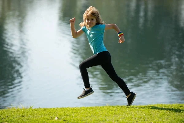 Děti běhají nebo běhají u jezera na trávě v parku. Kluci běhají po venkovním parku. Běh je sport, který posiluje tělo. Ranní jogging. — Stock fotografie