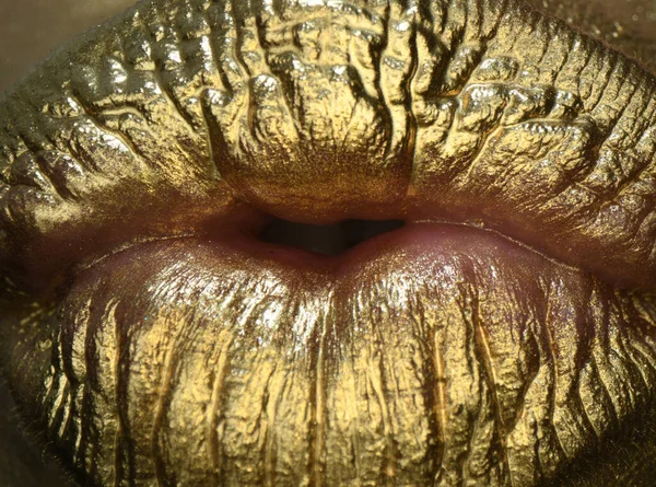 Golden kiss. Gold lips, golden lipgloss on sexy lips, metallic mouth. Beauty woman makeup close up. Glamour golden lips.