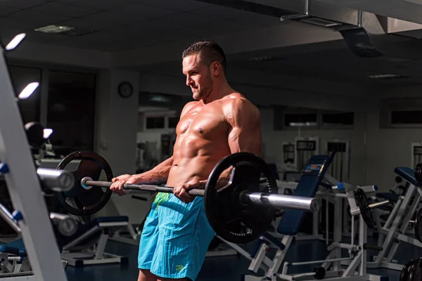 Deportivo haciendo bíceps levantando barra. Musculoso y fuerte chico haciendo ejercicio. Deportista haciendo ejercicios con pesas. Fitness y crossfit. — Foto de Stock