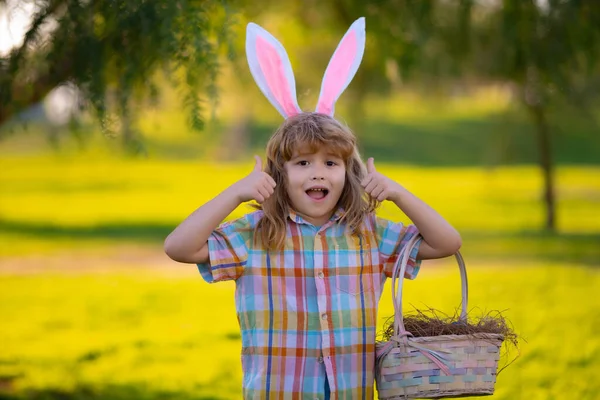 Feliz Páscoa. Miúdos a caçar ovos de Páscoa. Criança em orelhas de coelho caçam ovos de Páscoa. — Fotografia de Stock