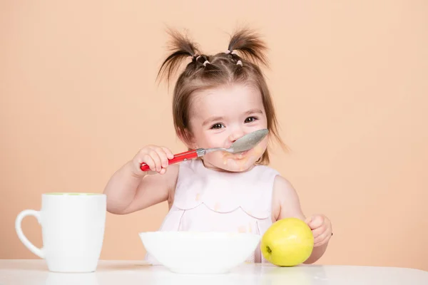 Милый ребенок ест пищу, дети едят. Счастливый улыбающийся ребенок с ложкой ест сам себя. — стоковое фото