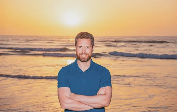 Schöner Mann im T-Shirt, der in einer Meereslandschaft posiert. Porträt eines fröhlichen Kerls, der den Sommerurlaub am Strand genießt. — Stockfoto