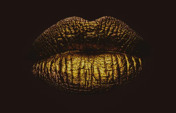 Golden lips closeup. Gold metal art lip. Beautiful makeup. Golden lip gloss on beauty female mouth, closeup. Sensual forms of woman lips.