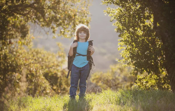 Słodki chłopiec ze sprzętem turystycznym w górach. Turysta dziecięcy z plecakiem wędrówka w tle wzgórza. — Zdjęcie stockowe