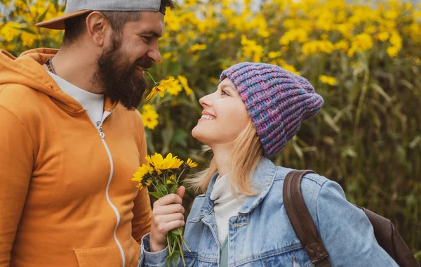 Genç aşık çift, sonbahar parkında çiçeklerle vakit geçirir. Erkeğin kucaklaması ve şehvetli bir kadını öpmesi. — Stok fotoğraf