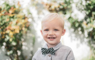 Mutlu çocuk portresi. Yakışıklı, neşeli, neşeli, komik, suratsız çocuk. Tasasız çocuk. Küçük çocuk yürümekten hoşlanıyor. Takım elbise ve papyon..