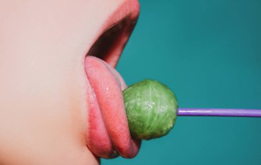 Ağız yalayan lolipop, kırmızı kadın parlak dudaklar ve pembe şeker lolipopu..