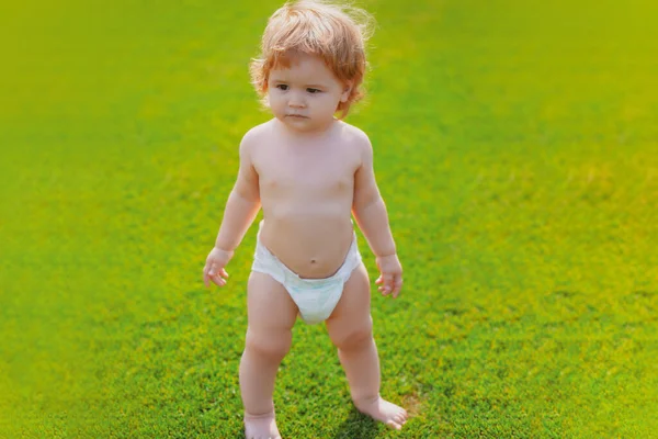 Hermoso bebé caminando en el parque en pantalones de pañal. Niño sano. —  Fotos de Stock