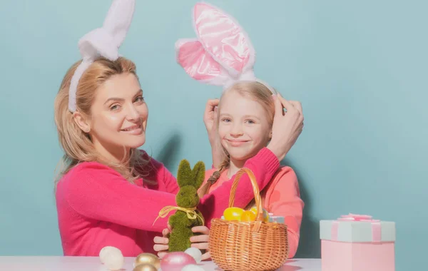 Matka i córka świętują Wielkanoc. Cute little girl z zabawną twarzą w uszach króliczka śmiejąc się, uśmiechając i bawiąc się izolowane na niebiesko. — Zdjęcie stockowe