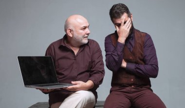 Oğul babasına modern teknolojiyi kullanmayı öğretiyor. Konuşurken ve gülümserken. Dizüstü bilgisayarla çalışan iki iş ortağı. İki iş arkadaşı bir dizüstü bilgisayarla eğlenceli projeleri tartışıyor..