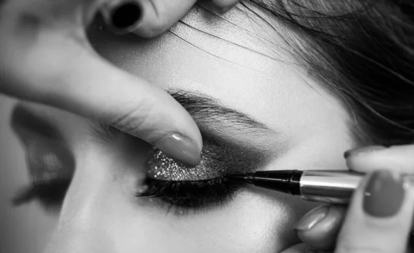 Närbild porträtt. Processen att göra makeup. En professionell make-up artist målar ögonfransar modeller i studion. — Stockfoto