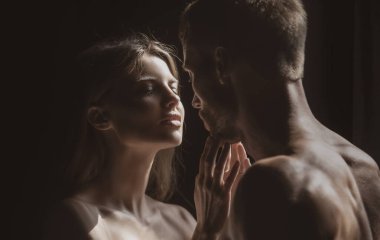 Birbirine aşık romantik bir çift siyah arka planda sarılıp öpüşüyor. Şehvetli çift öpücüğü. Ben de seni seviyorum. Romantik ve aşk.