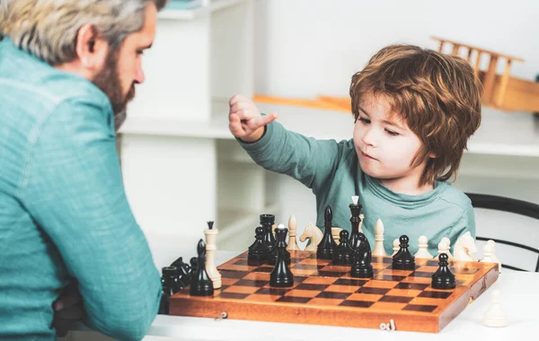 Vader met zoon die thuis schaak speelt. Terug naar school. Vader leert zijn zoon schaken.. — Stockfoto