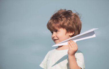 Aile seyahati ve tatil konsepti. Mutlu çocuk yaz gökyüzü arka plan karşı oyuncak uçak ile oynuyor. Mutlu çocuk. Kağıt aipplene ile sevimli çocuk.