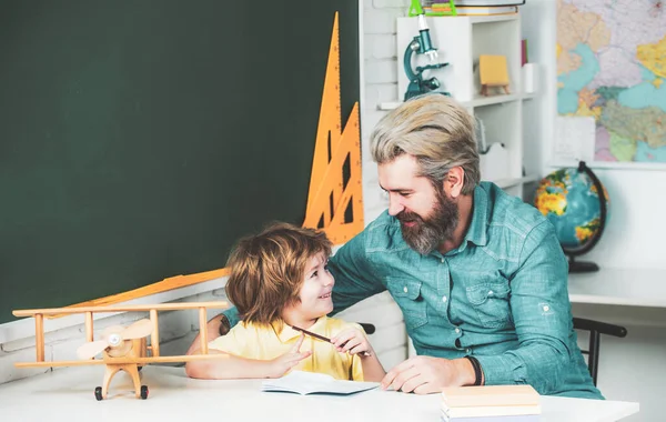 Kid a učitel se učí ve třídě na pozadí tabule. Soukromý doučovatel dětí. Základní škola a vzdělání. Otec pomáhá svému synovi s domácími úkoly. — Stock fotografie