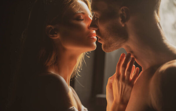 Portrait of lovely couple in love. Young sensual girlfriend glad to passionate kiss from her boyfriend. Handsome man embraces his woman and kisses. Sensual couple in the tender passion.