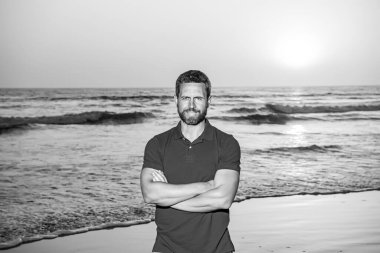 Yakışıklı, gülümseyen adam sahilde yaz gününün tadını çıkarıyor..