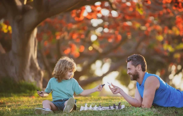 Famiglia felice all'aperto. Padre e figlio giocano a scacchi nel giardino autunnale. — Foto Stock