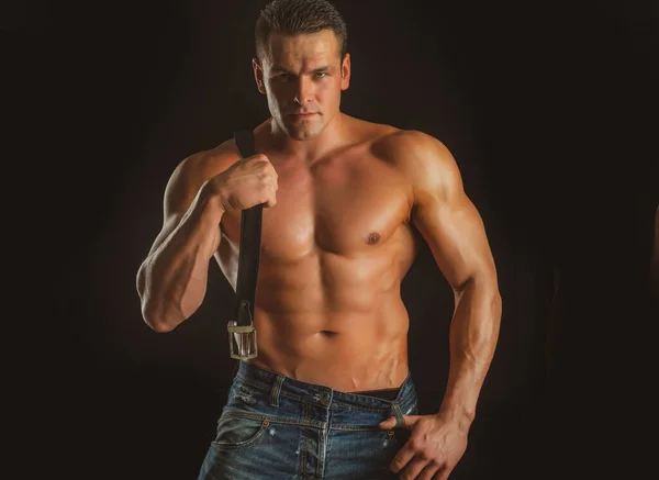 Brutal man with muscular body. Sexy young male holding leather belt. Bad guy. — Stock Photo, Image