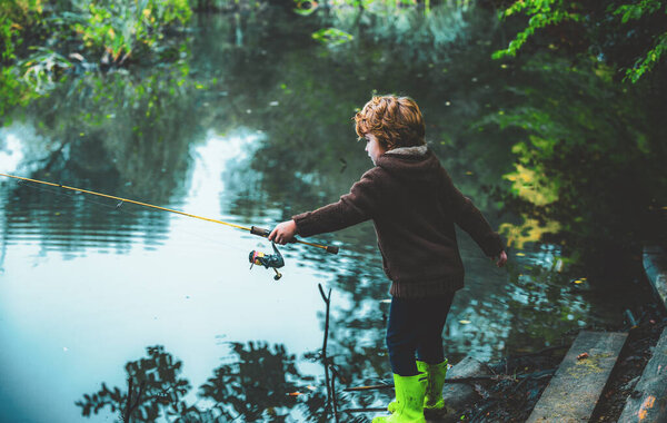 Cute child little boy pulling rod while fishing on lake.