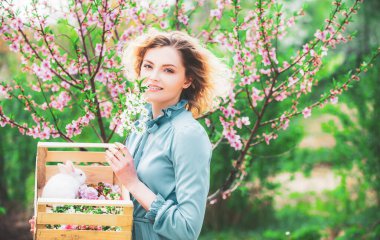 Bahar tarlasında çalışan sevimli kadın çiftçi. Bahar kadını bir bahar günü çiçeklerle arka planda.