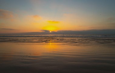 Gün batımında gökyüzü ve bulutların arasında güneş olan sakin bir deniz. Okyanus ve gökyüzü arkaplanı, deniz manzarası.