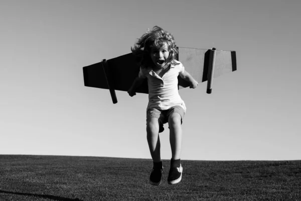 Grappig Kind springen en rennen met speelgoed jetpack. Kinderpiloot astronaut of ruimteman droomt van een vlucht. Aviator jongen vliegen met een kartonnen vleugels. — Stockfoto