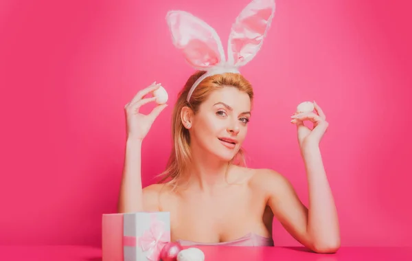 Tavşan kulaklı kadın paskalya yumurtasını pembe arka planda tutuyor.. — Stok fotoğraf