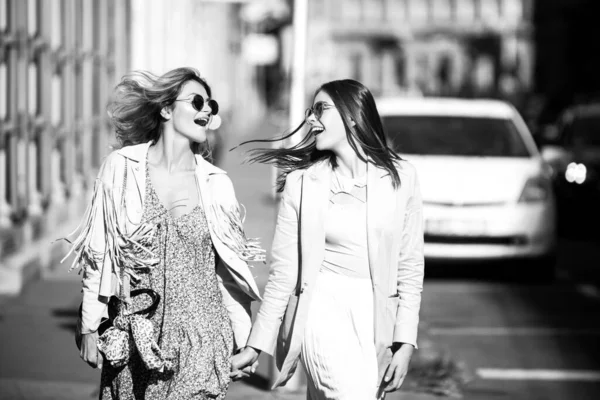 Две молодые женщины в солнечных очках ходят по городу. Забавный отпуск, романтические путешествия. — стоковое фото