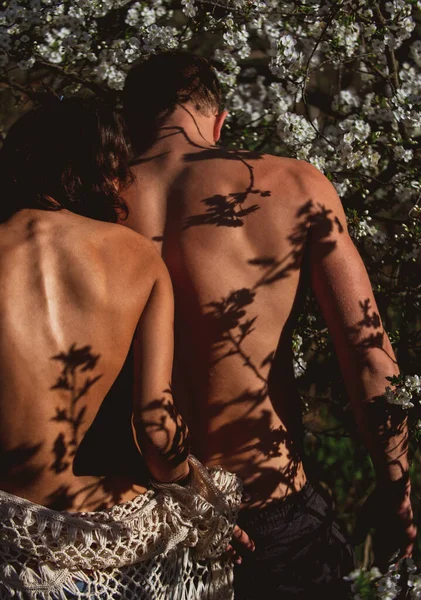 Coppia sensuale in fiore di ciliegio. Donna nuda uomo innamorato in fiore albero primaverile. Romanticismo, relazione, natura, concetto di ambiente. — Foto Stock