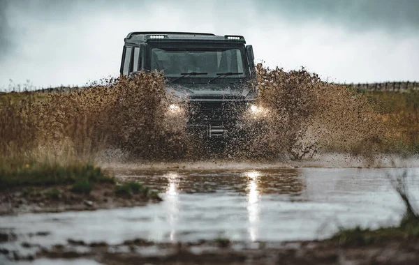 Mozgasd a kerekeket és a porban úszó terepjárókat. A vidéki esőzések után áthatolhatatlan úton ragadt terepjáró. — Stock Fotó
