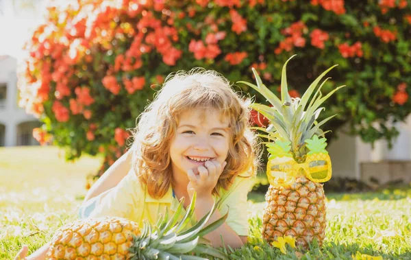 Menino segurando um abacaxi posando fundo natureza verão com espaço de cópia. Frutos saudáveis para o conceito de crianças. — Fotografia de Stock