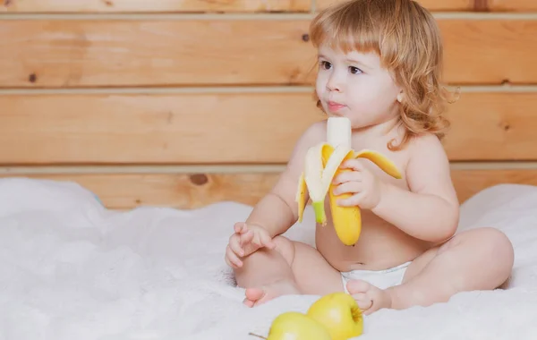 幸せな赤ん坊はバナナを食べる。新鮮な野菜や果物。子供の食事、栄養の概念. — ストック写真