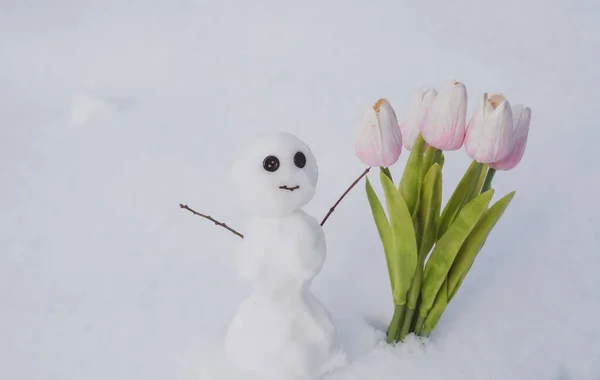 开着春天郁金香花的雪人。冬季雪人，手握木棍. — 图库照片