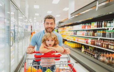 Alışveriş arabalı mutlu baba ve çocuk marketten ya da süpermarketten yiyecek alıyor..
