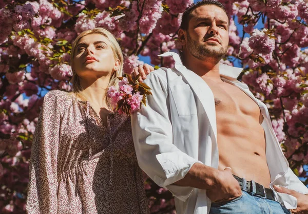 Sensuele vrouw en man in roze bloemen in de zomer bloesem park. Man en vrouw. — Stockfoto
