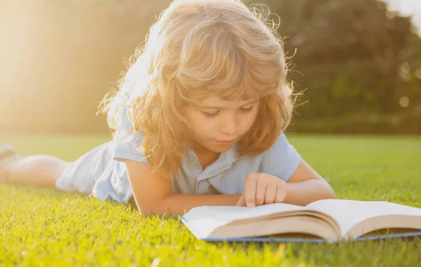 A gyerek pihenjen az ünnepekkor. Gyerek olvasni könyveket fű háttér. — Stock Fotó