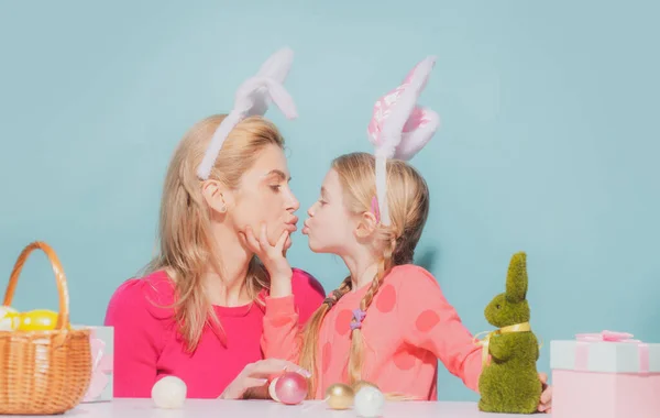 Anne ve kızı Paskalya 'da. Aile Paskalyayı kutlar. Tavşan kulaklı kızlar öpüşür, mavi renkte izole olur. — Stok fotoğraf
