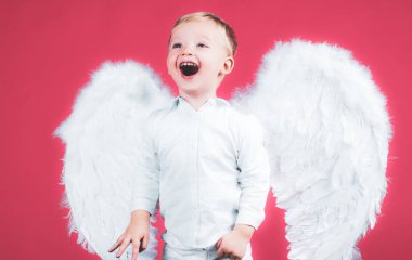 Gülümseyen, kıvırcık, sarışın, melek çocuk portresi. Melek gibi çocuk. Bebek melek gibi beyaz elbiseler ve tüylü kanatlar giyiyor. Masum çocuğun kutsallığı.