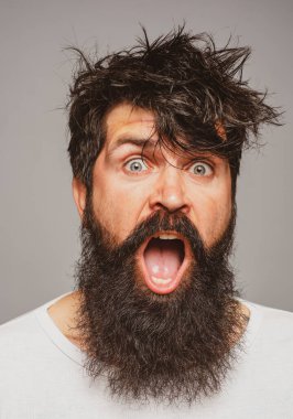 Sakallı ve bıyıklı bir adam. Şaşırmış ve heyecanlı görünüyor. Erkek saç kesimi, modern saç stili. Uzun saçlı erkek modelin yakın portresi. Sağlık ve saç bakımı sabah konsepti.